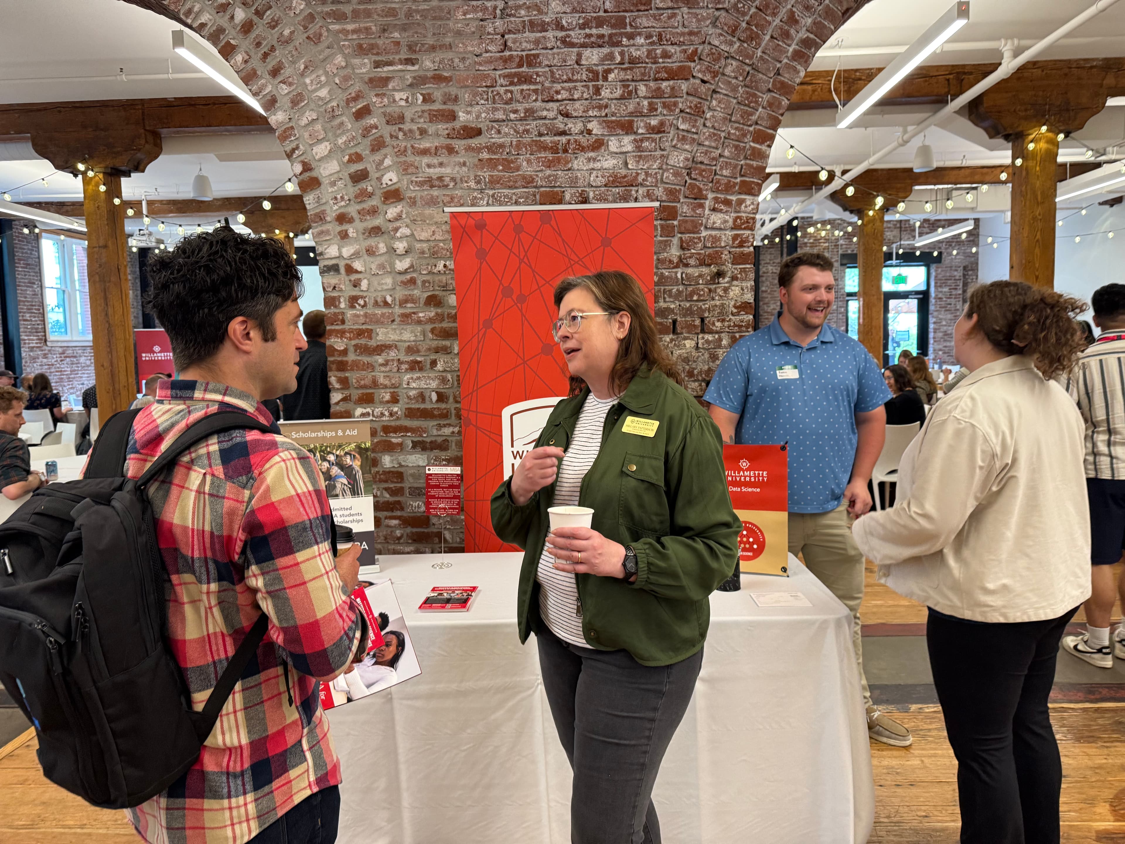 A sponsor booth conversation at an AI Portland event
